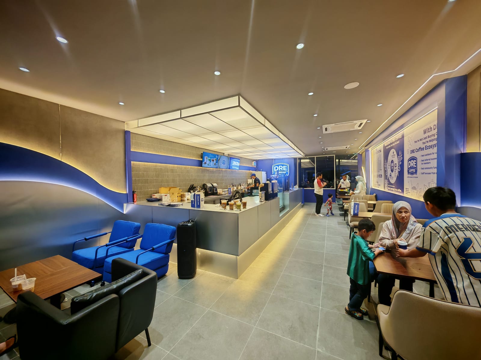Ruang dalaman kedai kopi dengan tempat duduk biru dan kaunter melengkung untuk DRE Coffee di Edusphare, Cyberjaya — fotografi projek